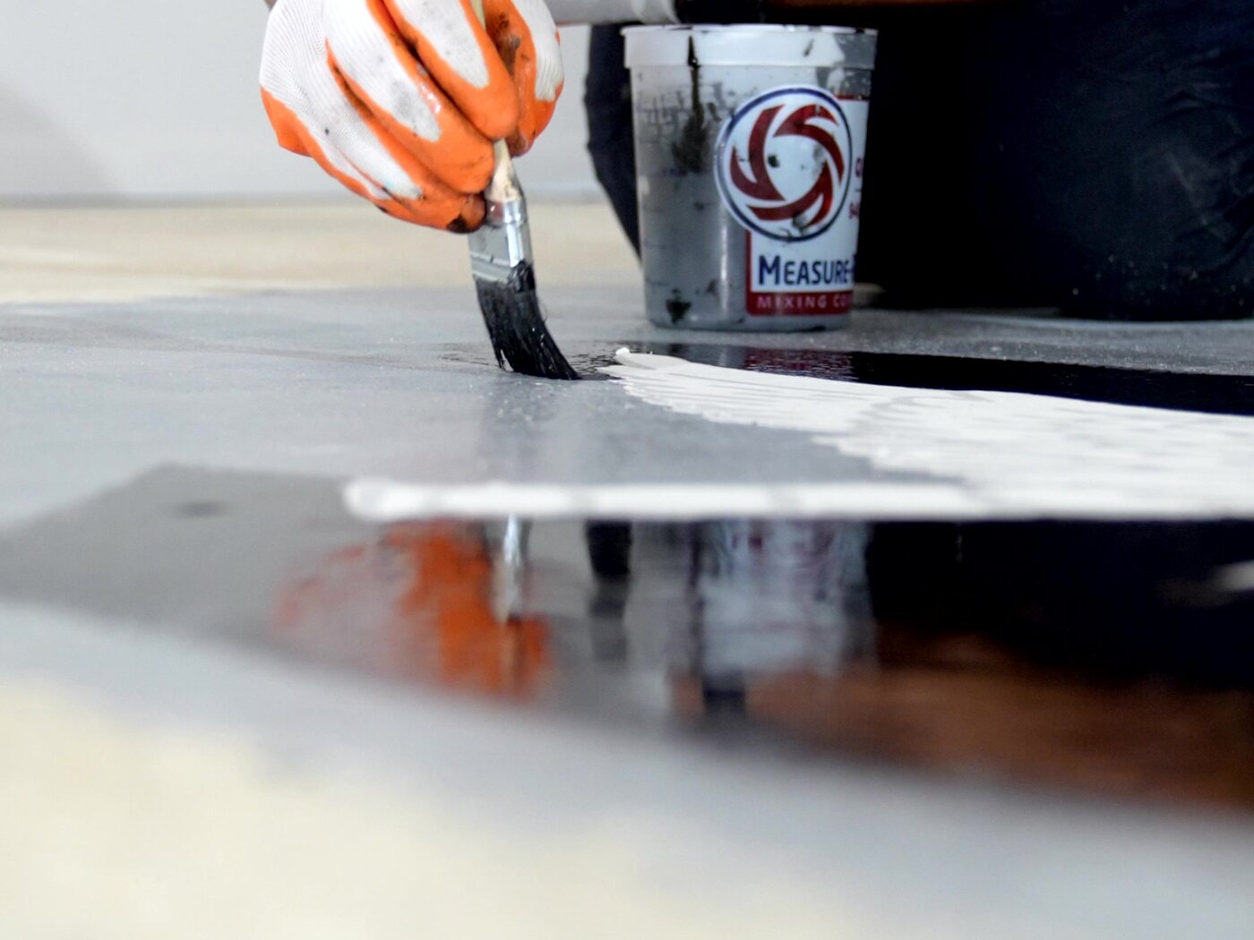 Coating worked by hand with a brush along the edge of a freshly poured, glass-wet interior floor