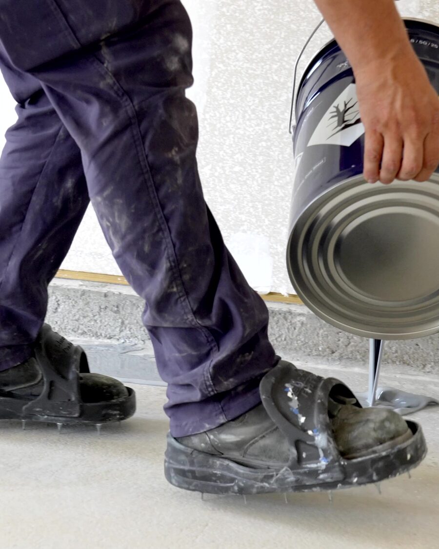 Pouring epoxy straight from the can onto a prepared slab, spiked shoes on