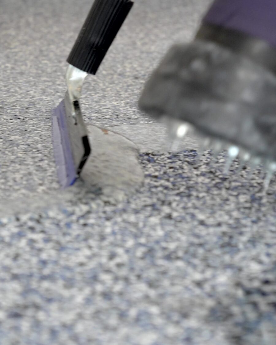 Topcoat being pulled across a blue-grey flake floor