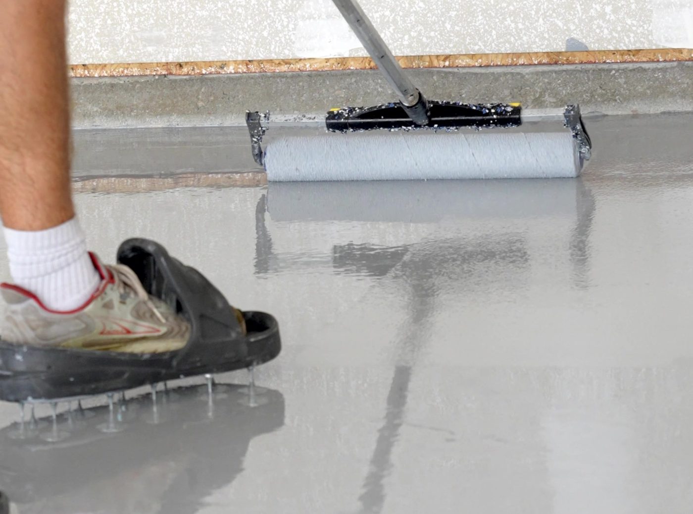 Sealer being pulled across a prepared concrete floor with a squeegee
