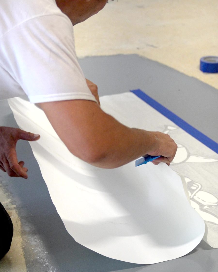 Peeling the backing from a custom floor stencil on a fresh base coat